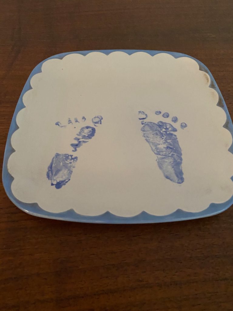 a homemade ceramic plate with two tiny footprints captured in blue paint, made when I was an infant